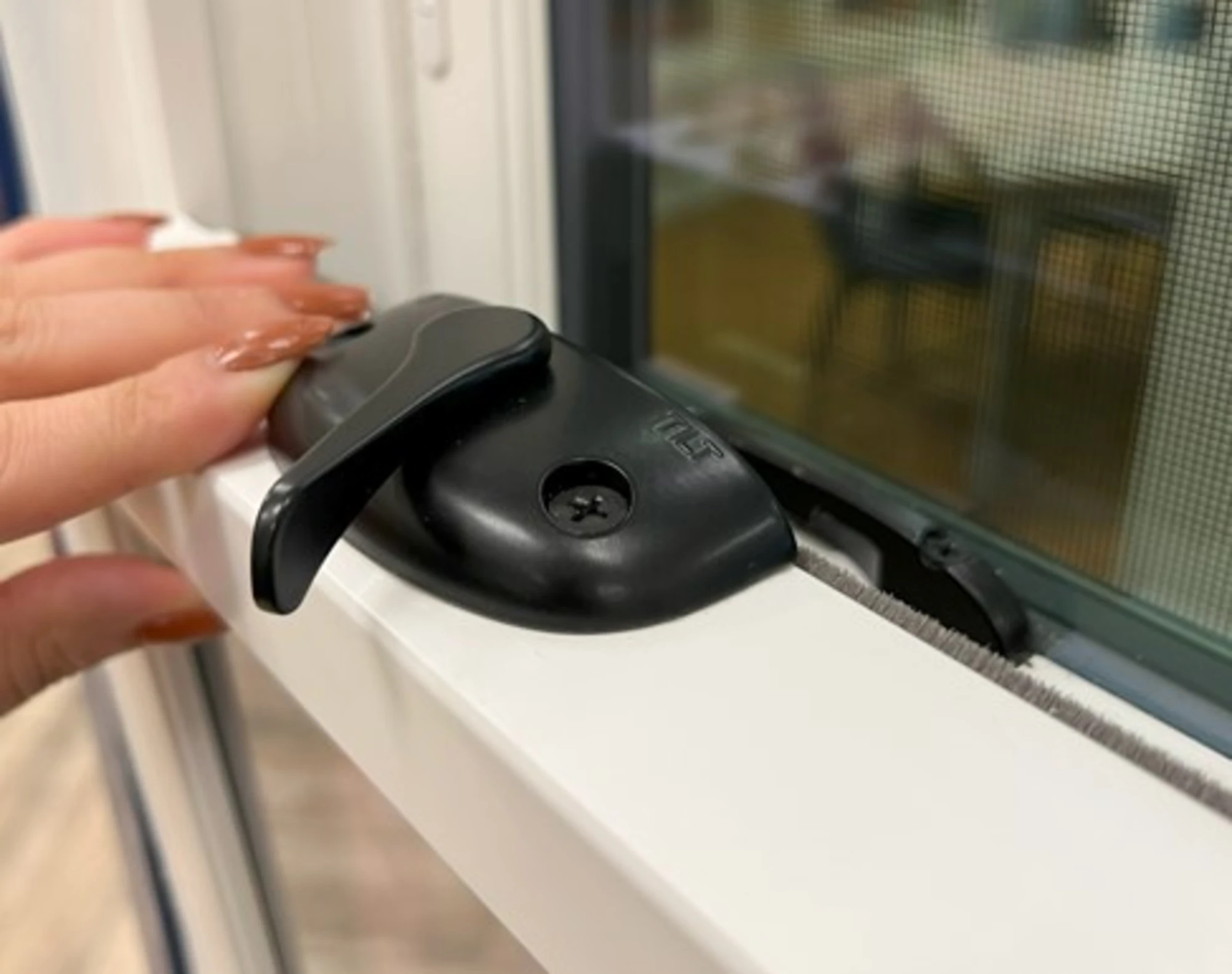 Close-up of a black window lock on a white double-hung window frame, showcasing secure and durable window hardware