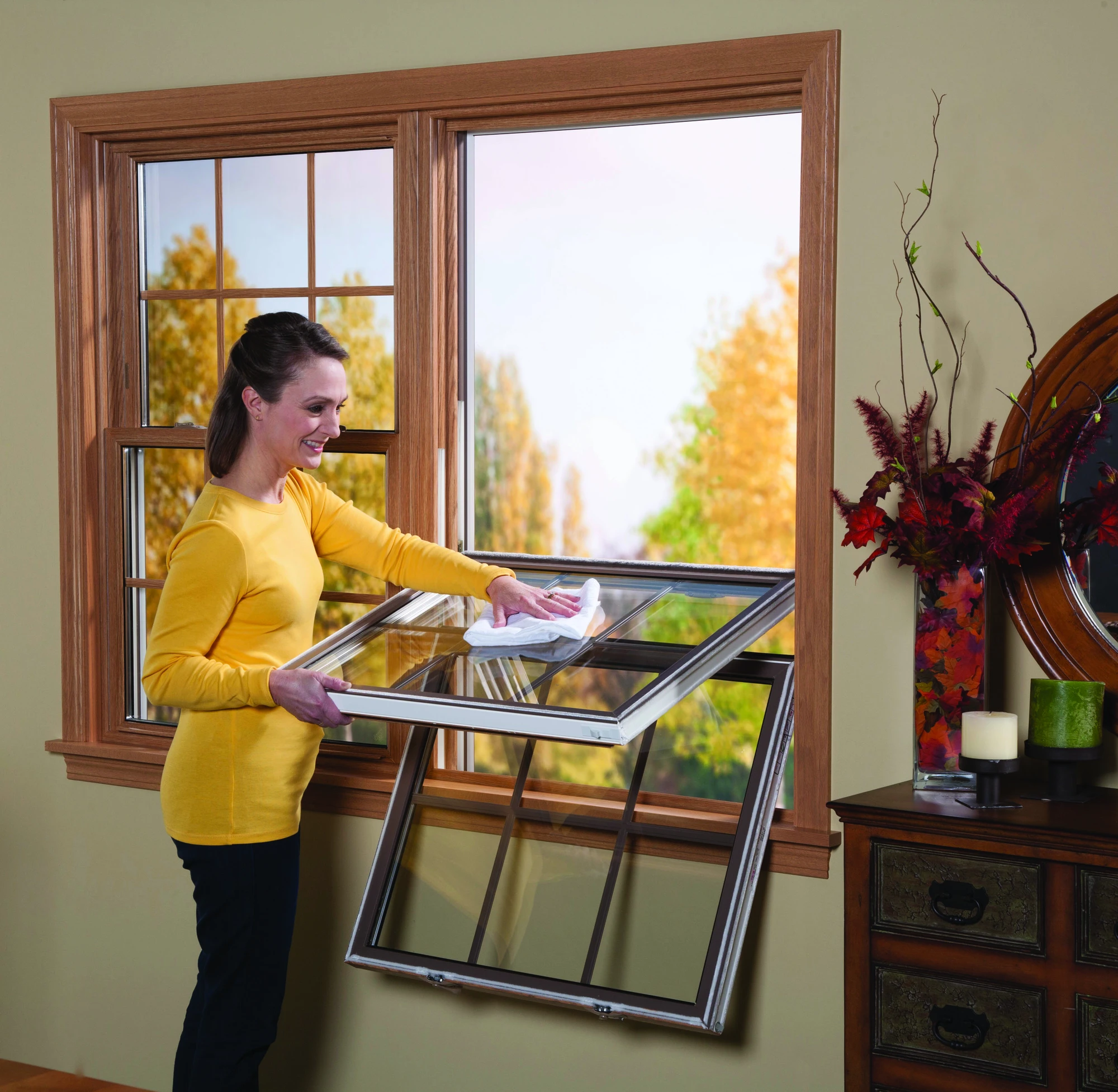 Woman cleaning a tilt-in double-hung window, demonstrating easy-to-clean bathroom window ideas that maintain both privacy and functionality