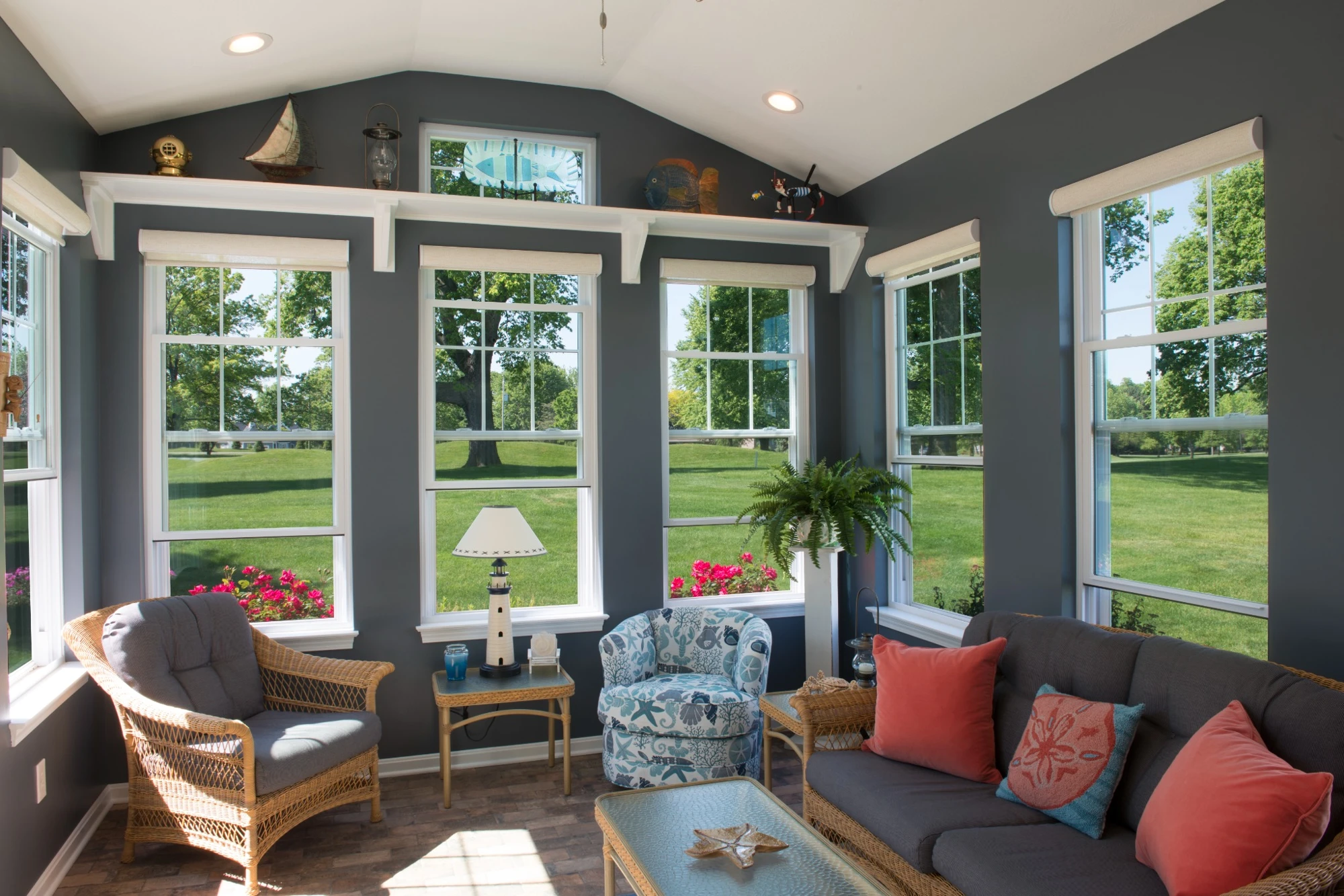 Bright sunroom with multiple large white-framed windows overlooking a green lawn, showcasing natural light and ventilation that help reduce condensation on inside of windows
