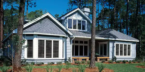 A beautiful home surrounded by trees featuring large bay windows that inspire modern bay window decorating ideas for bright, inviting spaces