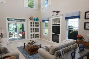 Bright coastal-style living room with large basement windows, a sliding glass door, and high ceilings letting in natural light