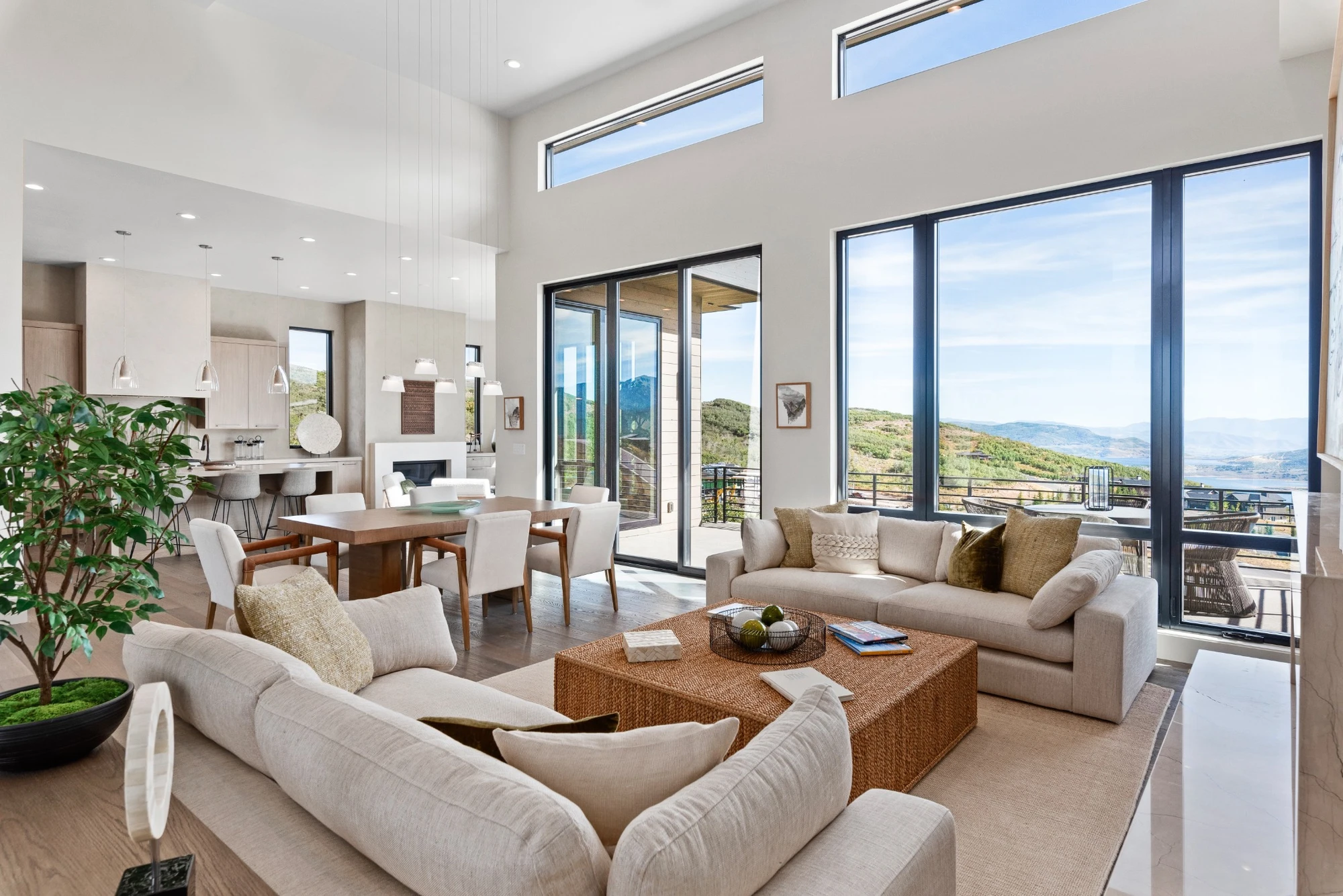 Floor to ceiling windows in a modern open-concept living and dining space, bringing in expansive views and abundant natural light