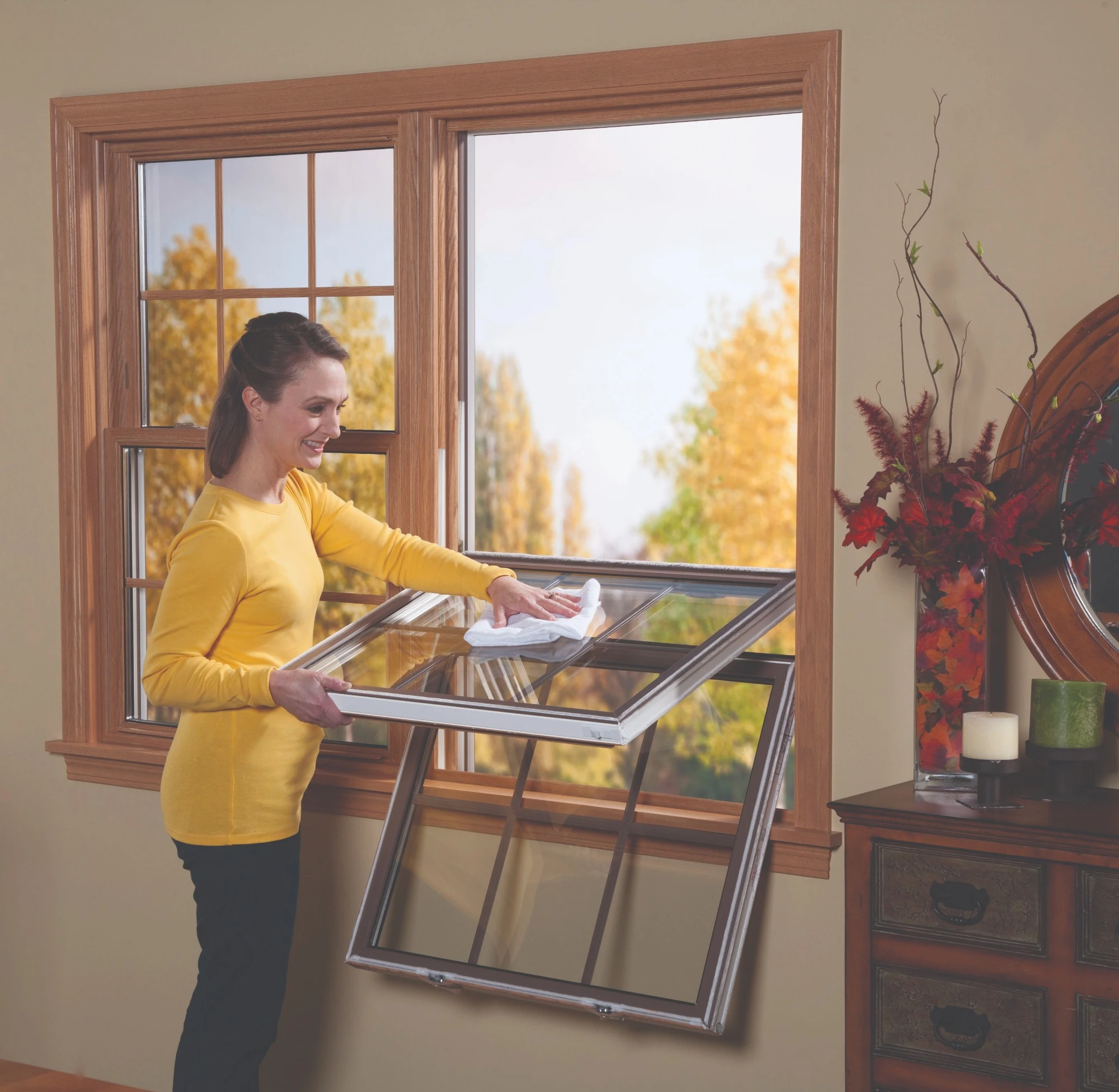 Single hung vs double hung windows comparison showing a homeowner cleaning a tilt-in double-hung window from inside the home