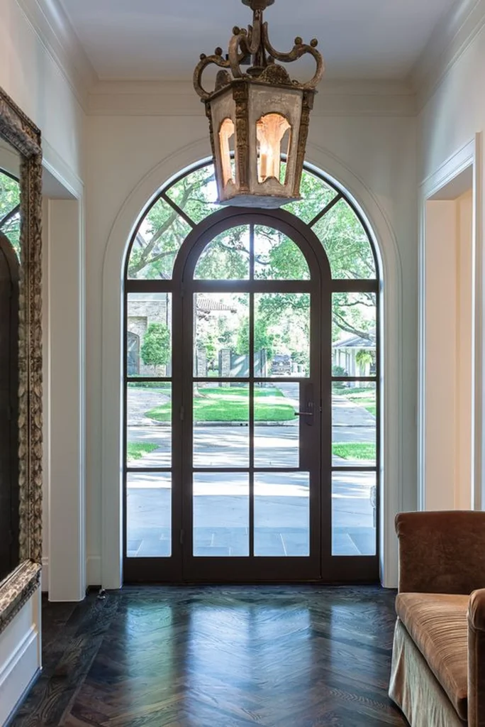 Elegant entryway featuring tall arched round windows with dark frames and divided panes bringing natural light into a luxury home