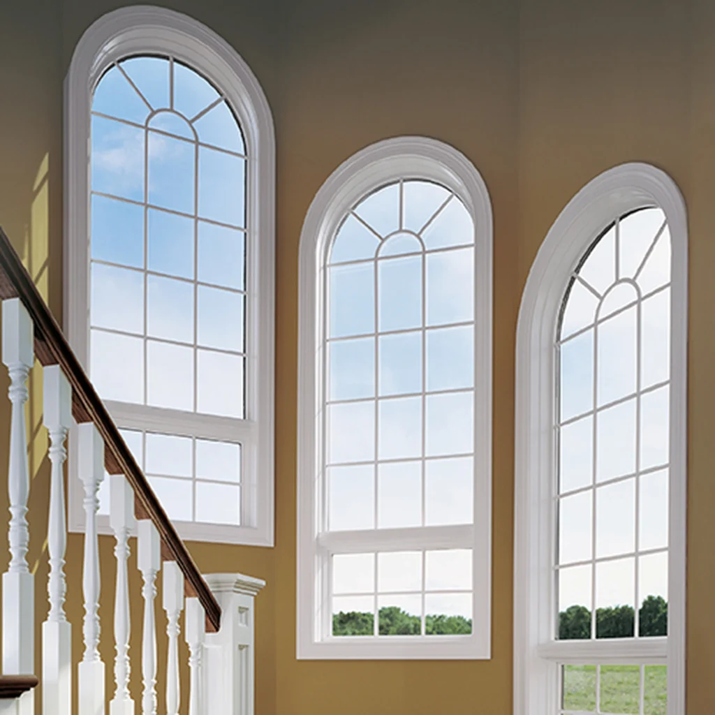 Elegant interior staircase featuring tall round windows with arched tops and white trim bringing in natural light