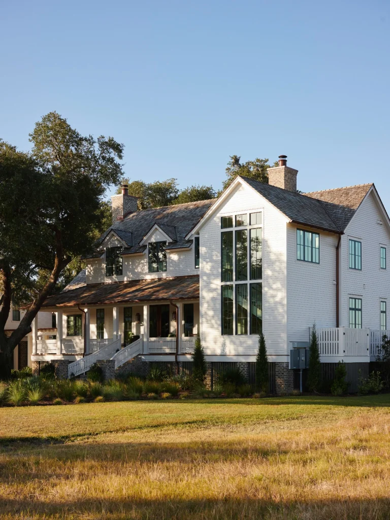Modern farmhouse exterior featuring large round windows and expansive glass panels enhancing natural light and curb appeal