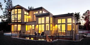 Image of modern home exterior featuring large fiberglass windows and doors at dusk