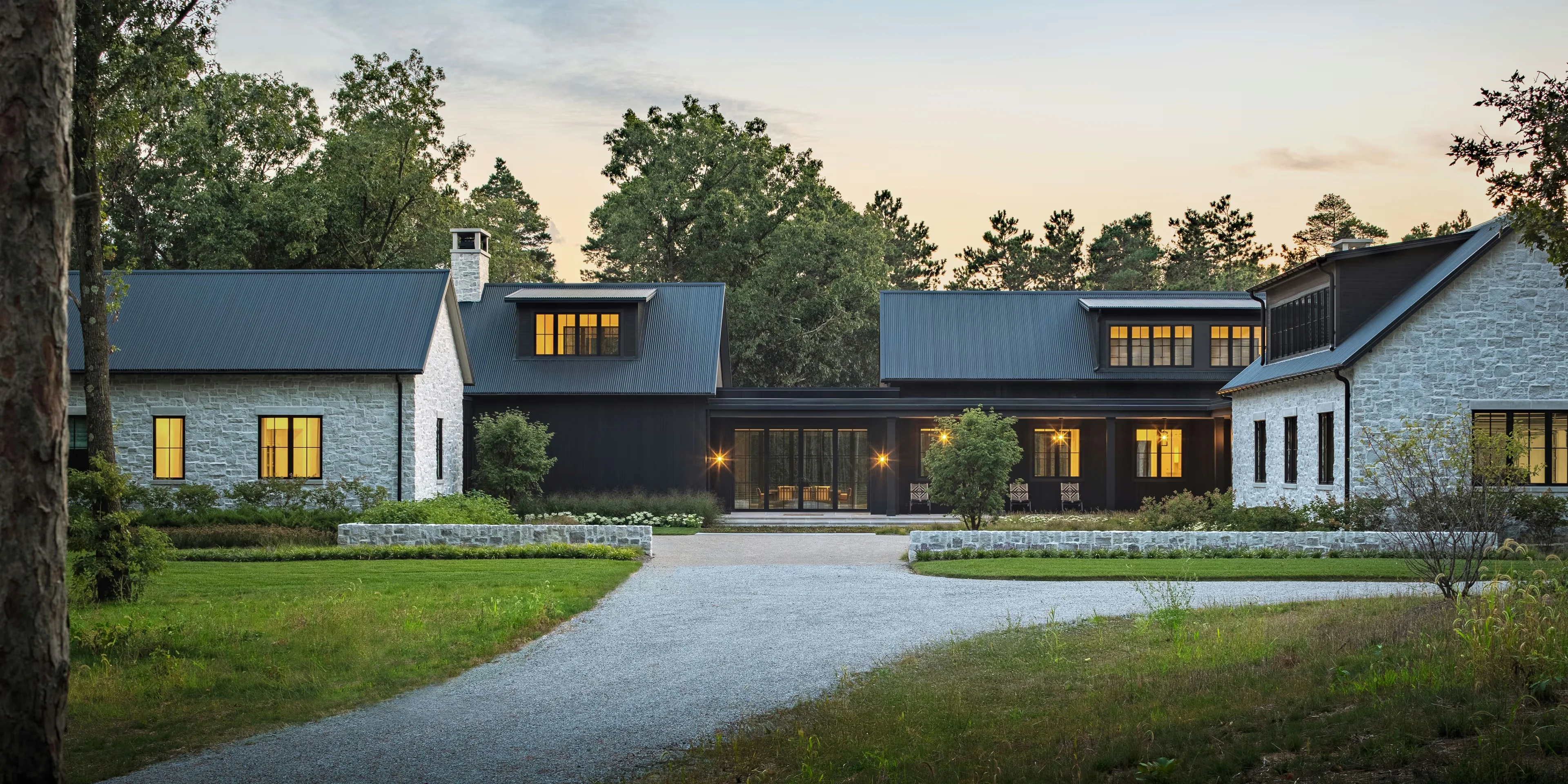 Image of a luxury stone home at dusk with glowing Marvin Ultimate windows across the facade