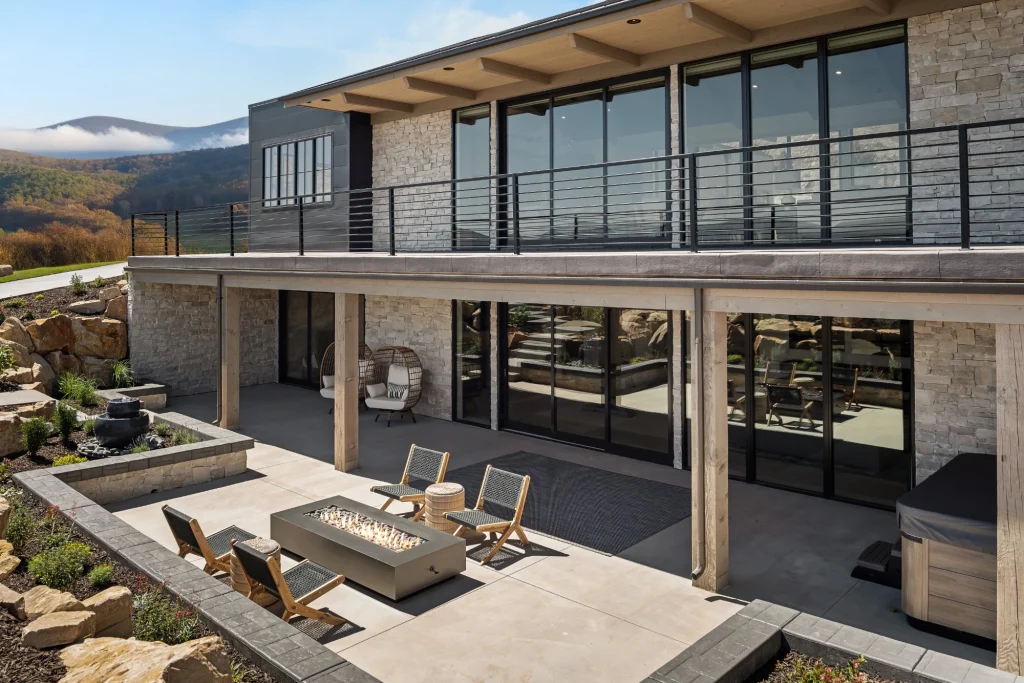 Image of a luxury modern home exterior featuring large aluminum-framed sliding windows and an outdoor patio
