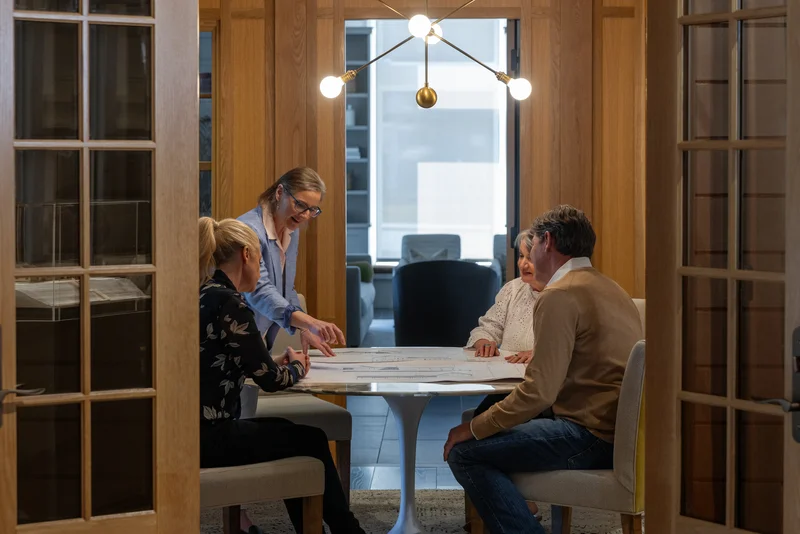 Image of a window replacement company consultant reviewing plans with homeowners at a table