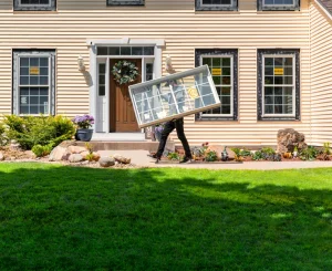 Image of are Marvin windows worth the price as installer carries replacement window unit to a colonial-style home