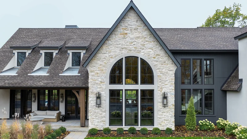 Image of best replacement window brands on a custom stone home featuring an arched window and premium craftsmanship