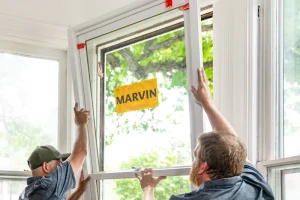 Image of two installers fitting a Marvin replacement window into a white interior frame