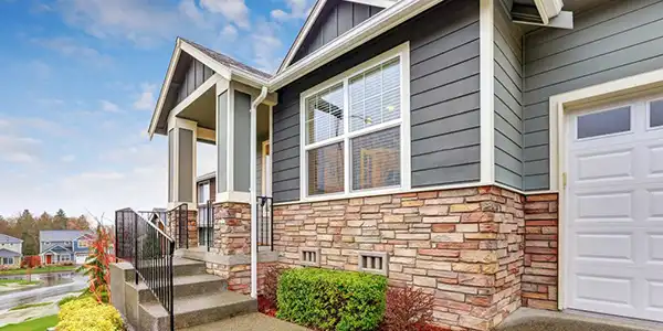 Image of vinyl replacement windows on a traditional suburban home with stone and siding exterior
