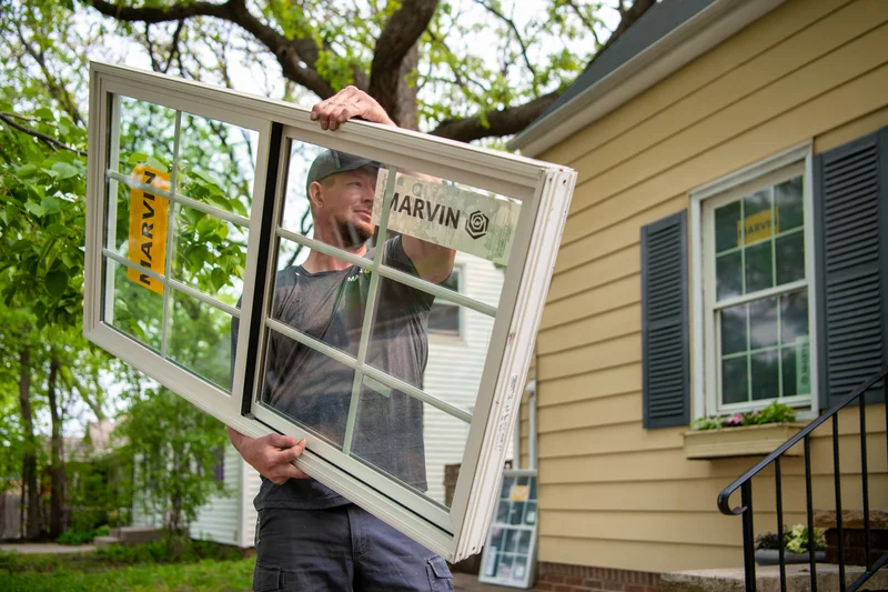 Image of a Marvin window installer carrying a certified window into a home for installation