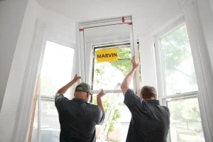 Image of a certified Marvin window installer team positioning a new window during installation