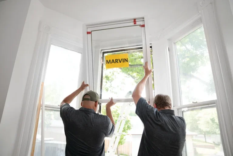 Image of a certified Marvin window installer team positioning a new window during installation